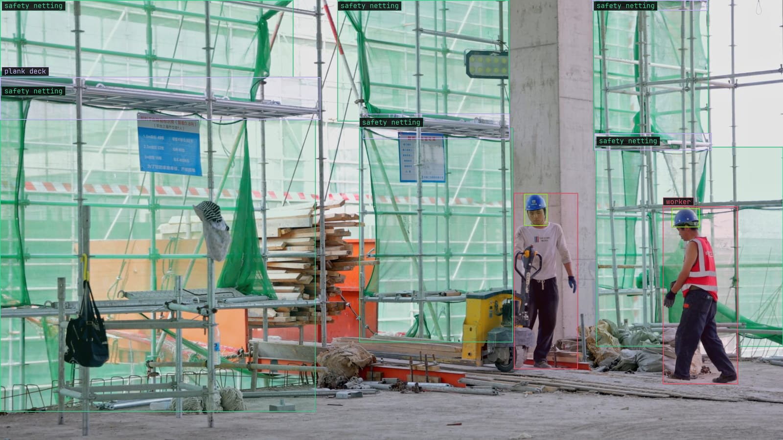 Two workers under scaffold netting with hard hats boxed, from a customer site camera