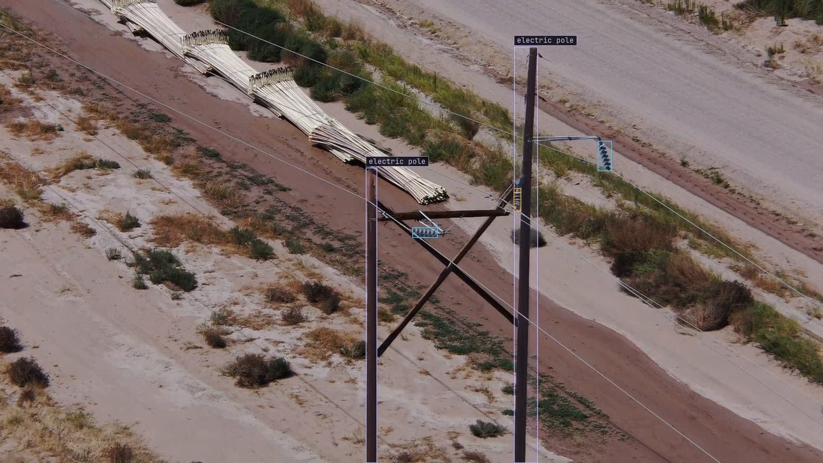 Distribution poles along a desert track, one insulator flagged as cracked, from a customer inspection run