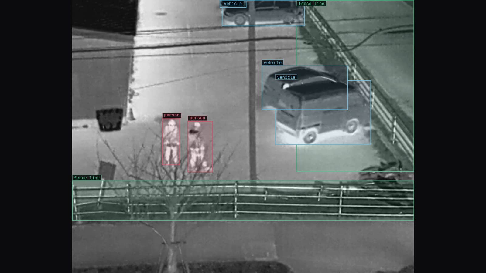 Thermal camera on a fence line at night, two people at the fence, vehicles and the fence line boxed, from a customer site camera