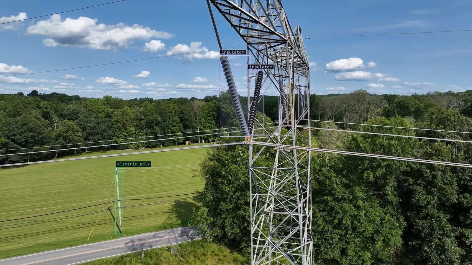 Lattice tower from a drone pass, insulator strings boxed and two corrosion spots flagged on the hardware, from a customer inspection run