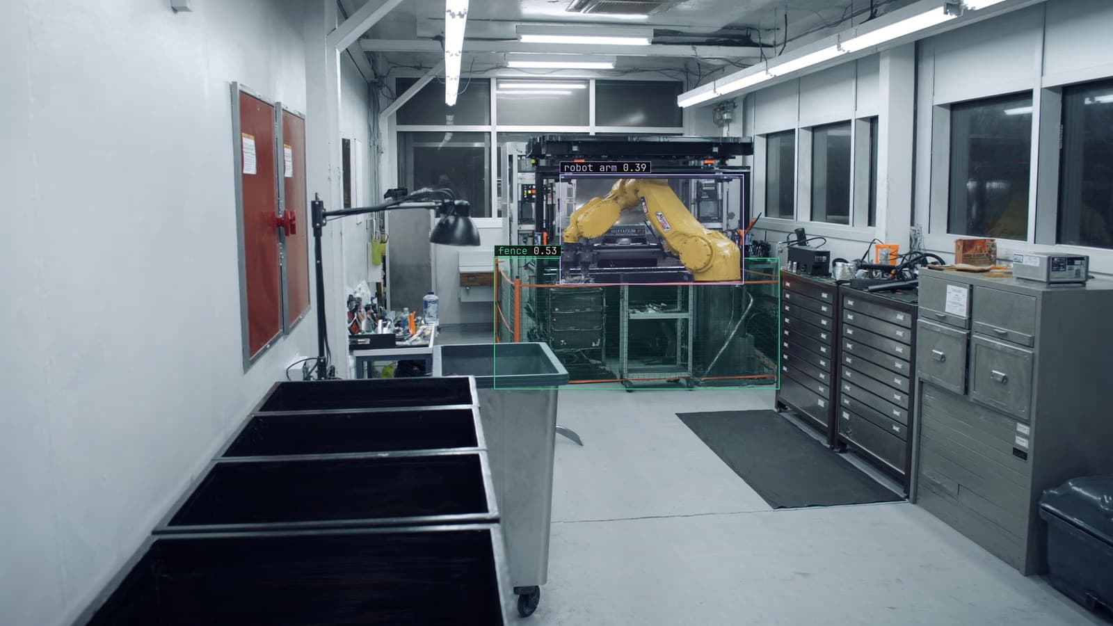 Factory floor with the robot cell fence boxed, generated scene with detections from our model, the kind of frame a crew inside the fence turns unfamiliar