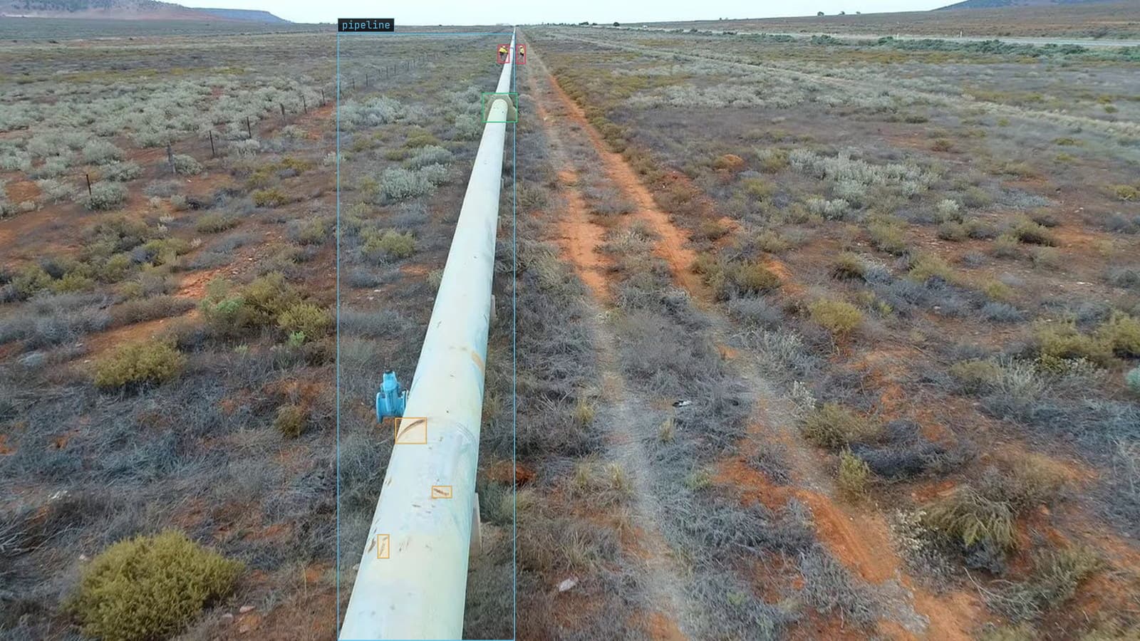 Drone pass along a desert pipeline, rust spots flagged and two people and a cradle boxed, from a customer drone survey