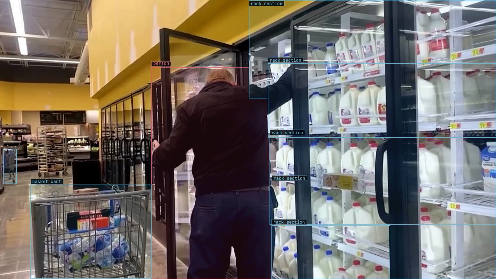 Shopper at an open dairy case, partly behind the door, rack sections and two carts boxed, from a customer store camera
