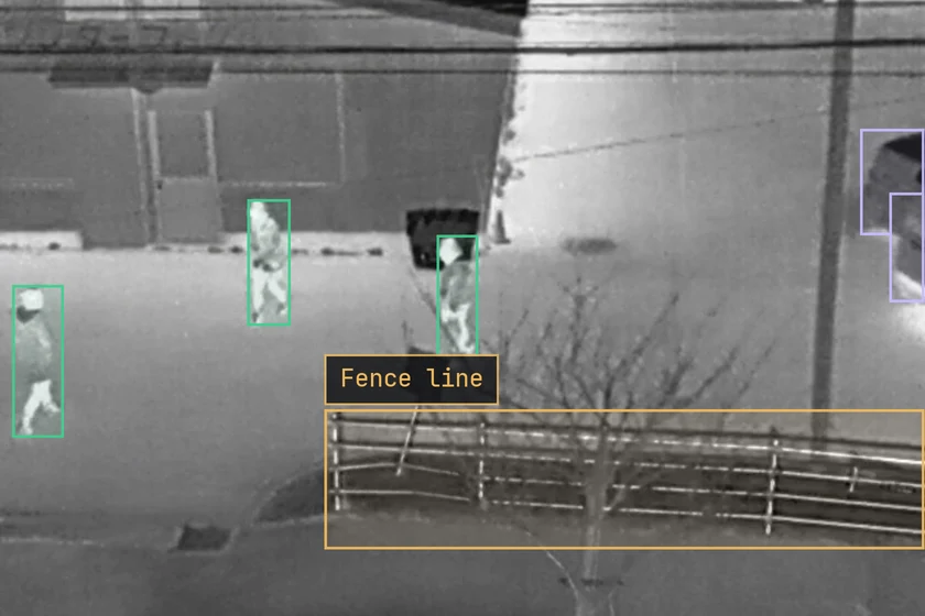 A thermal frame with three people and the fence line boxed